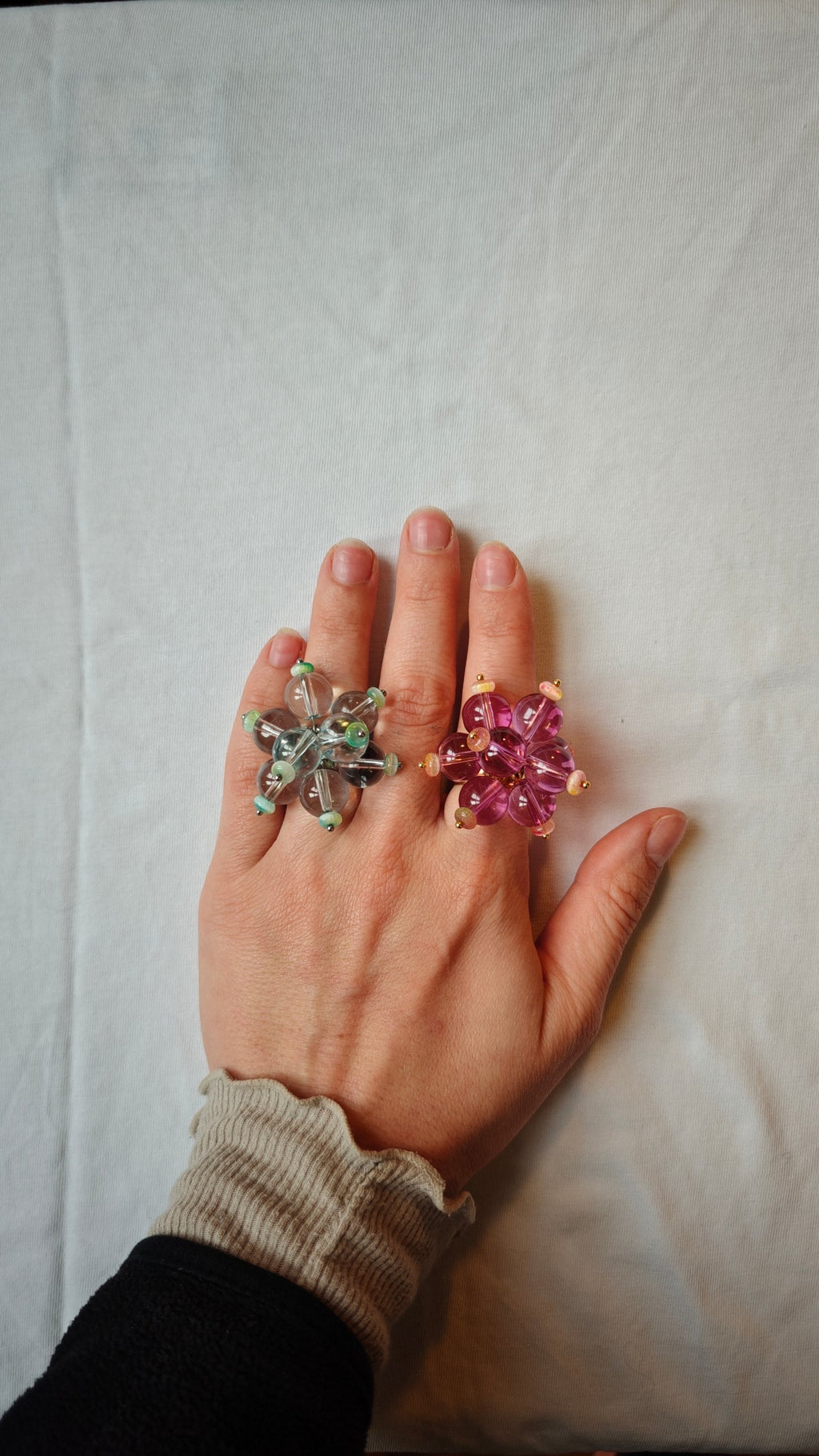 Bague turquoise et bague rose et violet dorée portées ensemble sur une main
