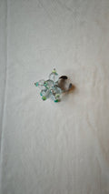 Bague ajustable en perles de verre transparentes et rondelles turquoise, posée à plat