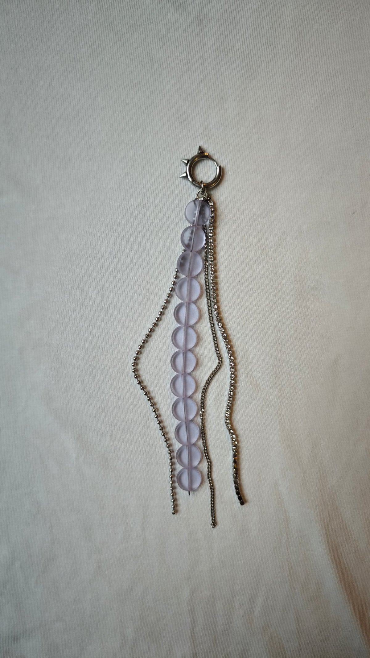 Mono boucle d'oreille de palets lilas mats et de trois chaînes dont une chaîne strass, avec anneau à pics en acier