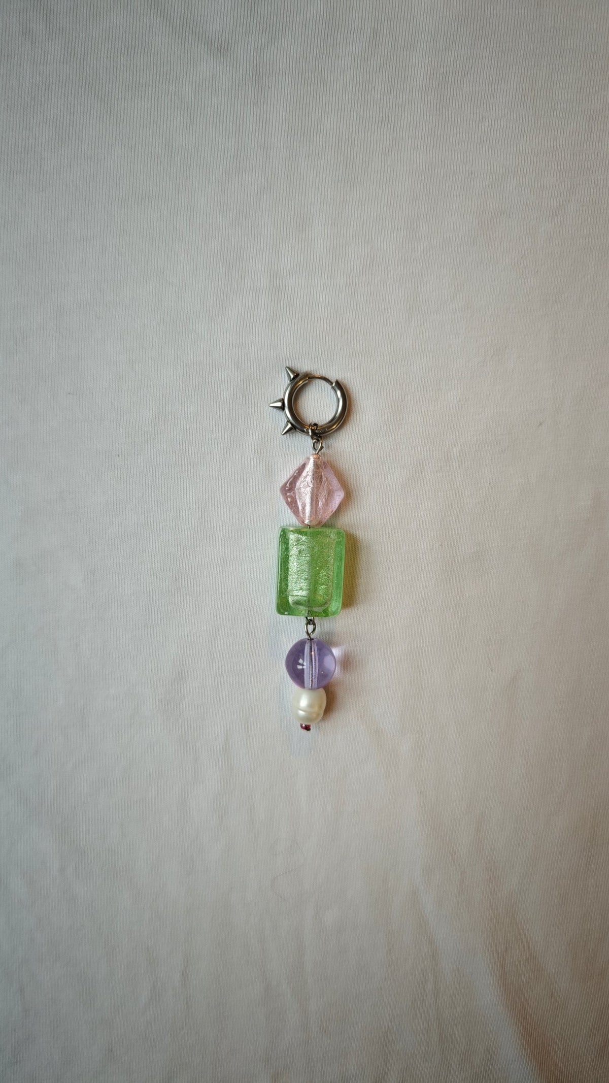Mono boucle d'oreille avec un losange rose, un rectangle vert, une perle lilas et une perle blanche, avec anneau à pics