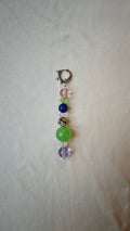 Mono boucle d'oreille composée de perles multicolores dont une perle dalmatienne et une grosse perle verte, avec anneau à pics