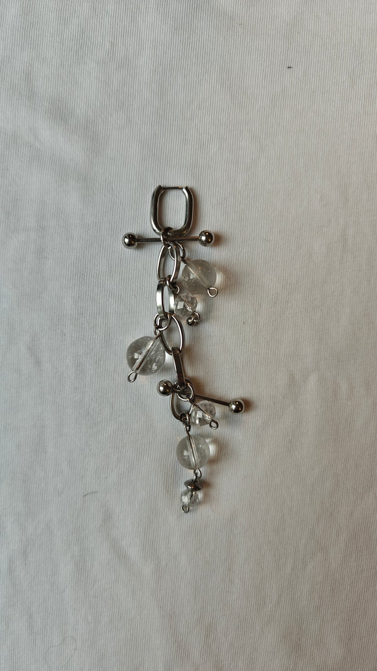 Mono boucle d'oreille de perles transparentes, chaîne à gros maillons et deux barres en acier, posée à plat