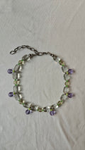 Collier de perles transparentes et vert pâle avec des pampilles rondes lilas, posé à plat