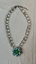 Collier de perles transparentes avec une fleur de perles bleu ciel à pois noirs et une perle verte au centre