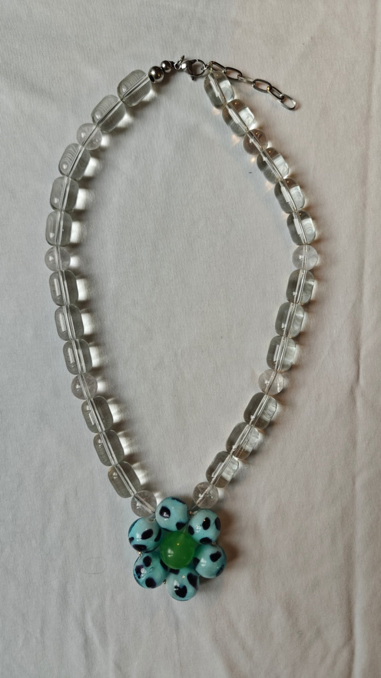Collier de perles transparentes avec une fleur de perles bleu ciel à pois noirs et une perle verte au centre